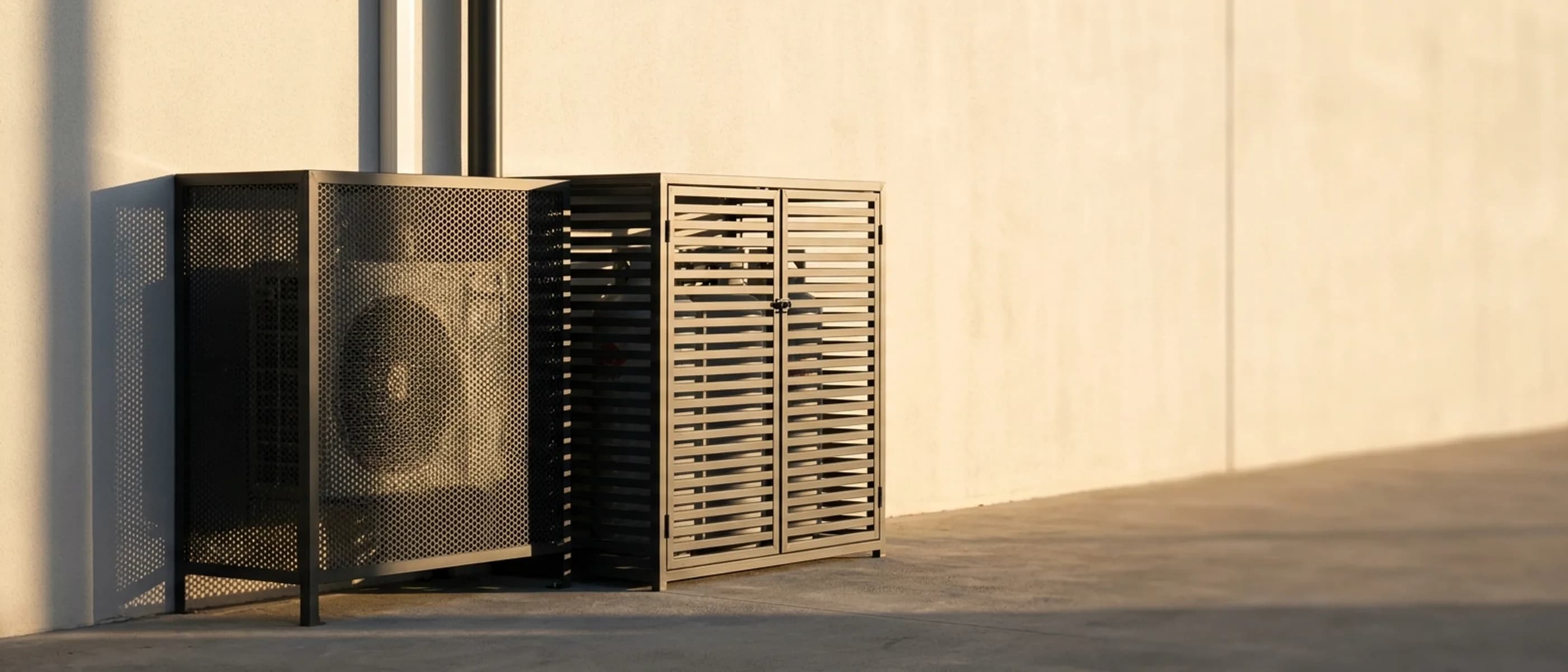 Aluminium aircon cover and gas cylinder cage mounted against a plastered exterior wall