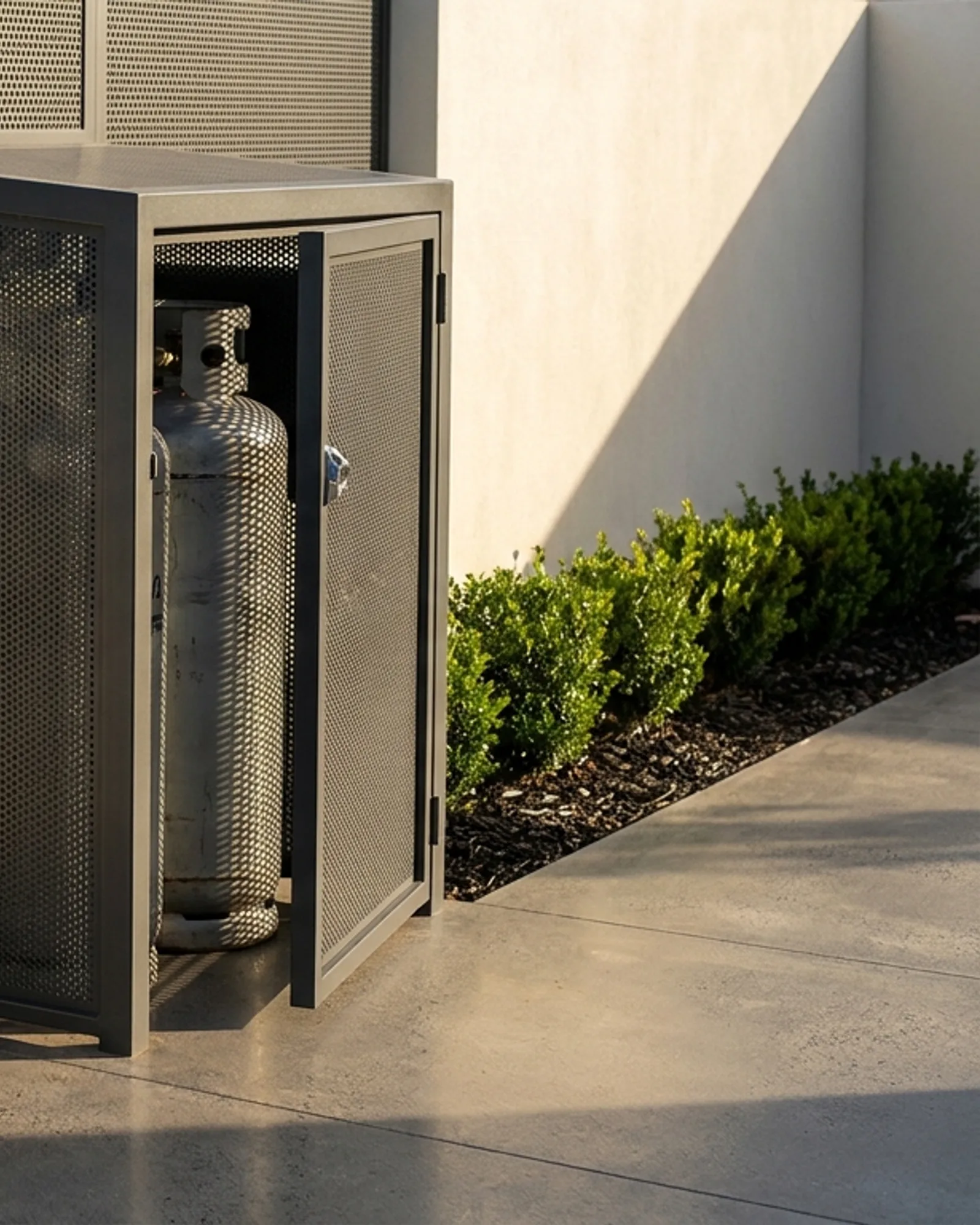 Charcoal ventilated aluminium gas cylinder cage against a garden wall with the door ajar
