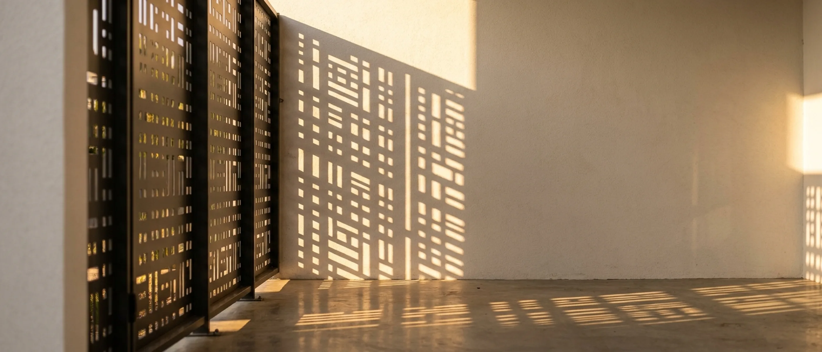 Laser-cut aluminium privacy screen casting a patterned shadow on a plaster wall